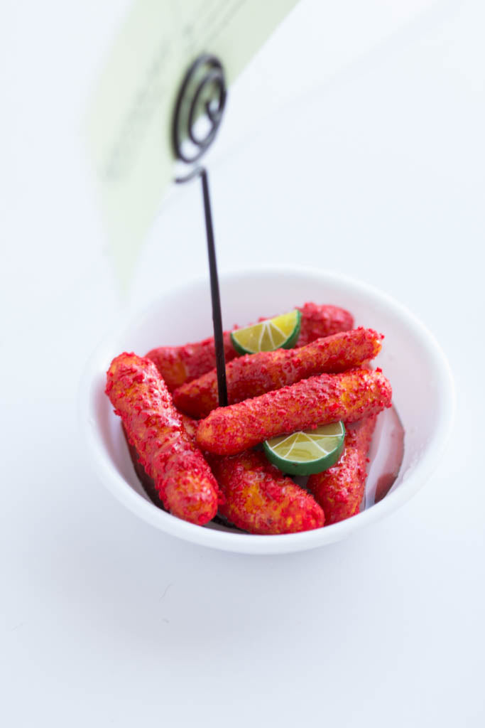 Handmade hot cheeto chips with miniature lime slices in a white bowl